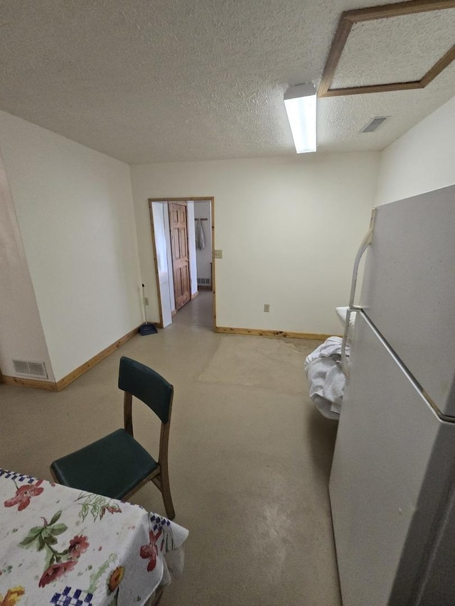 interior space featuring a textured ceiling, baseboards, and visible vents