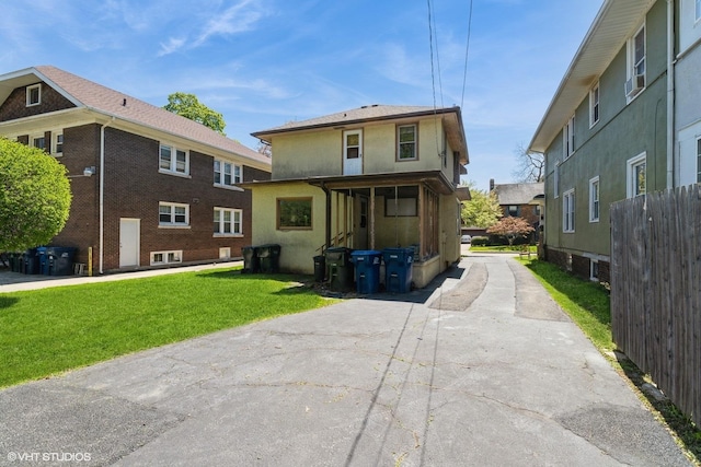 back of house with a lawn and stucco siding