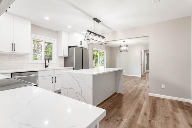 2705 Arlene Dr, Urbana, IL 61802 - kitchen with stainless steel appliances, a center island, a sink, light wood finished floors, and tasteful backsplash