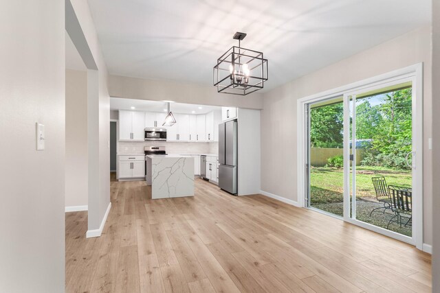 2705 Arlene Dr, Urbana, IL 61802 - kitchen featuring stainless steel appliances, a chandelier, white cabinets, baseboards, and light wood-style floors