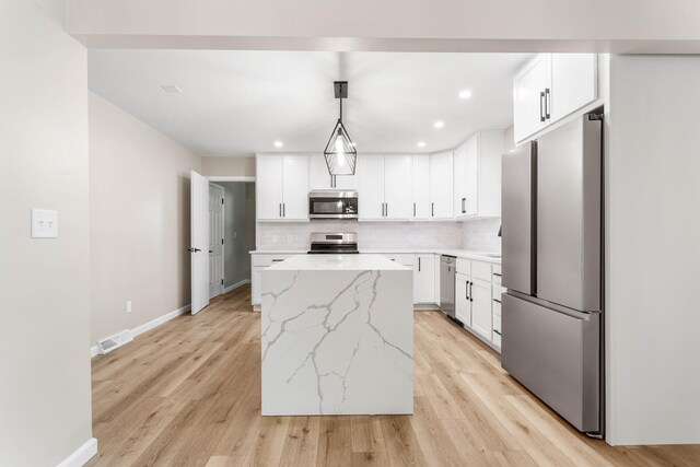 2705 Arlene Dr, Urbana, IL 61802 - kitchen featuring appliances with stainless steel finishes, a kitchen island, backsplash, light stone counters, and white cabinetry