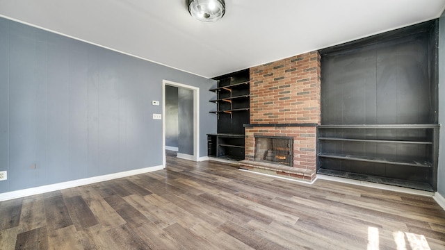 630 Willett Ave, Dixon, IL 61021 - unfurnished living room with wood finished floors, baseboards, a brick fireplace, and built in features