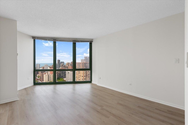 111 W Maple St Unit 3001, Chicago, IL 60610 - unfurnished room with expansive windows, wood finished floors, a view of city, a textured ceiling, and baseboards