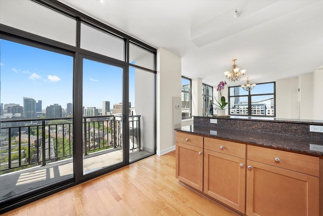 233 E 13th St Unit 2209, Chicago, IL 60605 - kitchen featuring a chandelier, light wood-style floors, dark stone counters, a skyline view, and decorative light fixtures