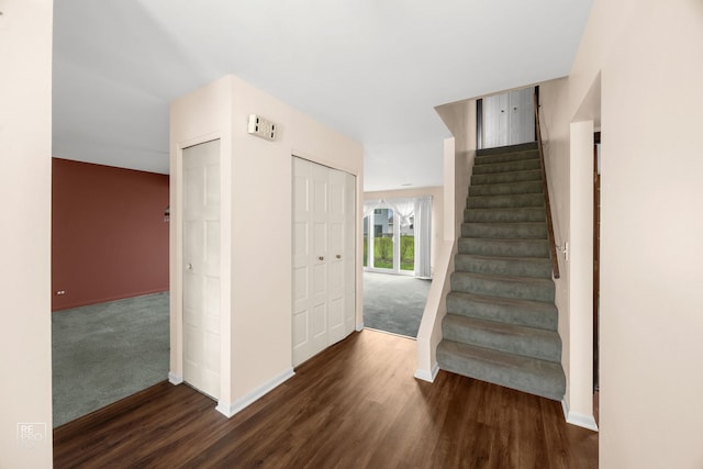 staircase with baseboards, wood finished floors, and carpet