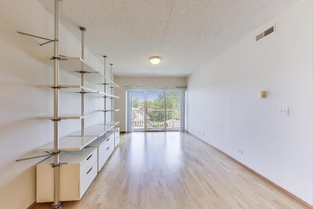 6560 W Diversey Ave Unit 412D, Chicago, IL 60707 - unfurnished room with light wood-style flooring, a textured ceiling, and baseboards