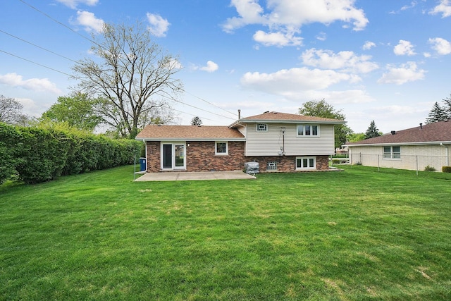 rear view of property with brick siding, a patio area, fence, and a lawn