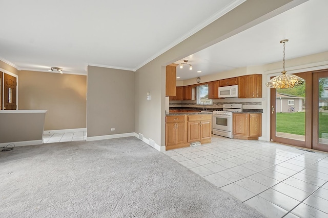 kitchen featuring white appliances, a sink, plenty of natural light, crown molding, and dark countertops