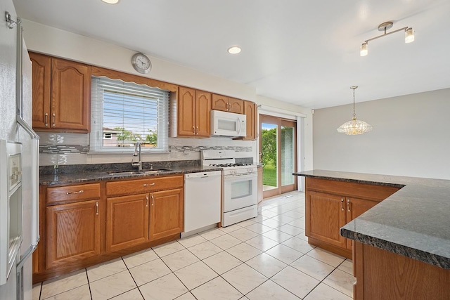 kitchen featuring a sink, brown cabinetry, white appliances, and a healthy amount of sunlight