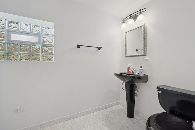 bathroom with toilet, baseboards, and marble finish floor