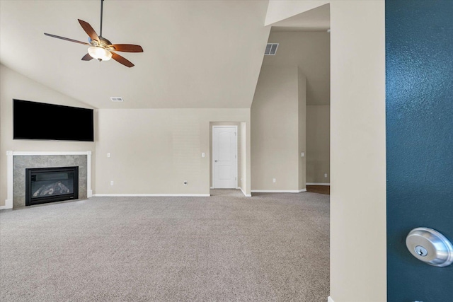 unfurnished living room with lofted ceiling, ceiling fan, carpet floors, a glass covered fireplace, and baseboards