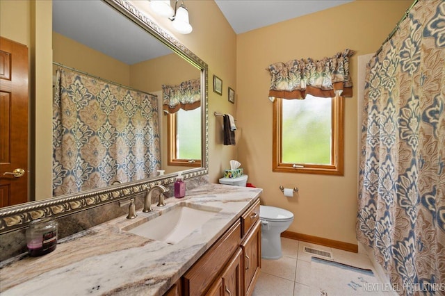 bathroom featuring healthy amount of natural light, tile patterned flooring, toilet, and vanity