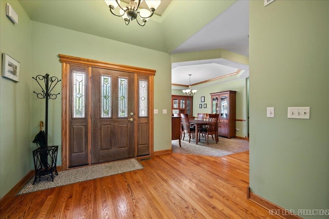 foyer featuring a chandelier, light wood-style flooring, plenty of natural light, and baseboards