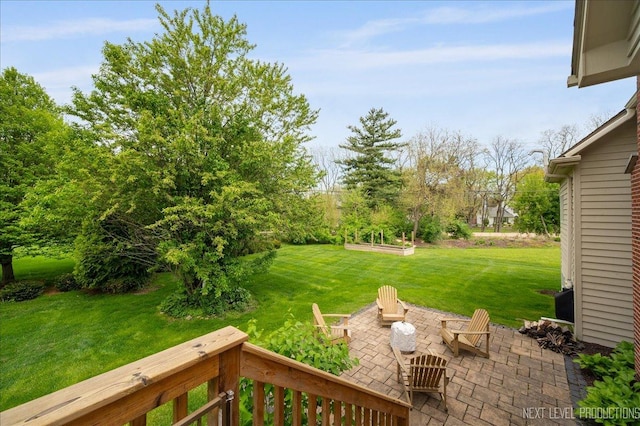 view of green lawn featuring a patio area and an outdoor fire pit