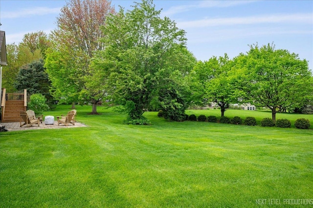 view of grassy yard featuring an outdoor fire pit and stairs