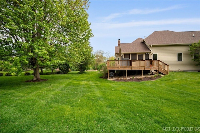 rear view of property with a chimney, a deck, and a yard