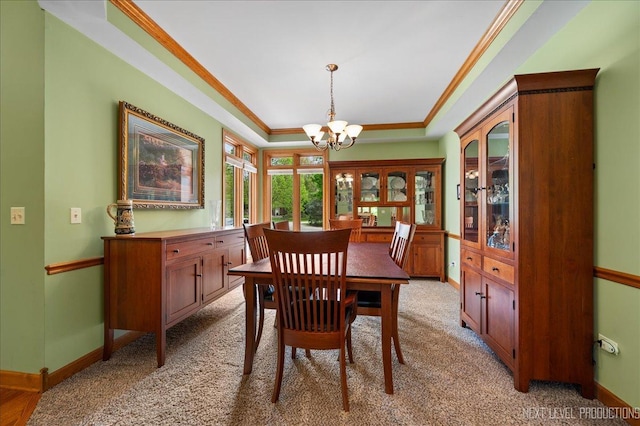 dining area featuring a chandelier, baseboards, ornamental molding, light colored carpet, and a raised ceiling