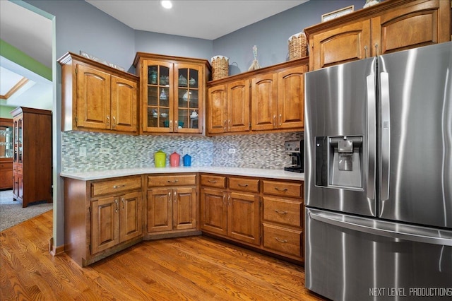 kitchen with stainless steel refrigerator with ice dispenser, brown cabinetry, and light countertops