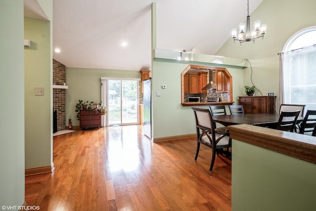 1319 President St, Glendale Heights, IL 60139 - dining space featuring high vaulted ceiling, an inviting chandelier, light wood-style flooring, a brick fireplace, and baseboards