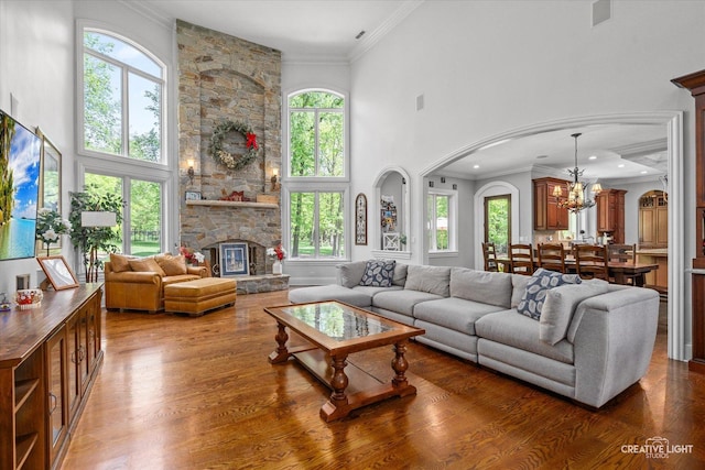4779 Lees Ct, Oswego, IL 60543 - living area featuring arched walkways, a chandelier, wood finished floors, a high ceiling, and ornamental molding