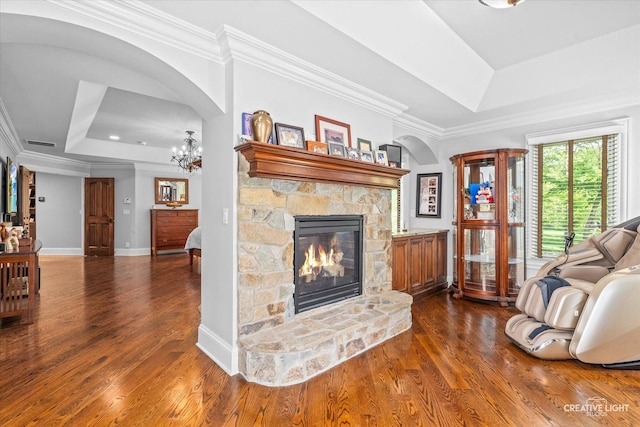 4779 Lees Ct, Oswego, IL 60543 - living room with a tray ceiling, crown molding, arched walkways, dark wood-style flooring, and a stone fireplace