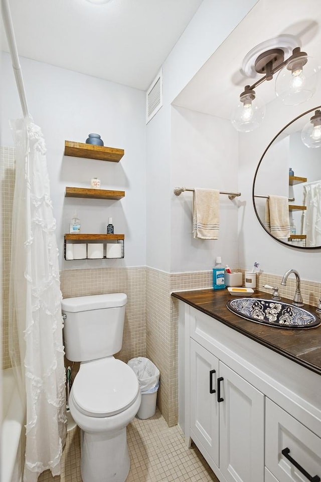 260 E Chestnut St Unit 1706, Chicago, IL 60611 - bathroom featuring toilet, vanity, tile patterned floors, wainscoting, and tile walls