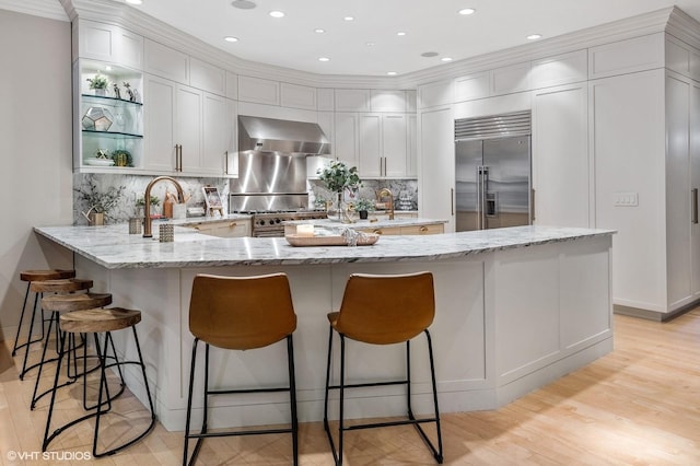 1442 W Cuyler Ave, Chicago, IL 60613 - kitchen featuring a peninsula, light wood-style flooring, open shelves, high quality appliances, and wall chimney range hood