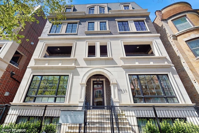 view of front of house featuring a balcony and mansard roof