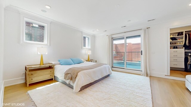 bedroom with light wood finished floors, access to outside, a walk in closet, recessed lighting, and baseboards