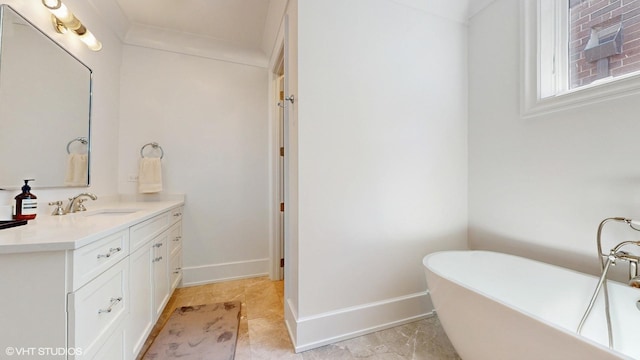 full bathroom featuring vanity, a freestanding bath, and baseboards