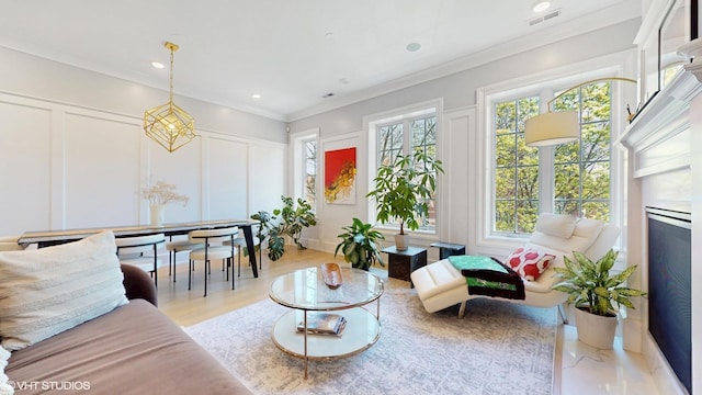 living area with a decorative wall, ornamental molding, and recessed lighting