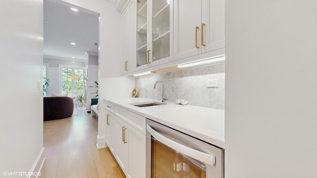 bar with stainless steel dishwasher, decorative backsplash, light wood-style floors, recessed lighting, and a sink