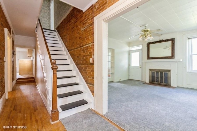 1027 Paul St, Ottawa, IL 61350 - staircase featuring a fireplace with flush hearth, a ceiling fan, wood finished floors, and brick wall
