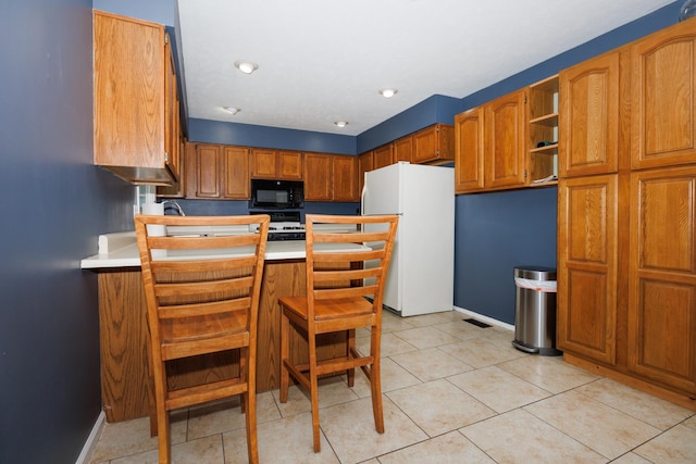 107 Regal Dr, Normal, IL 61761 - kitchen featuring freestanding refrigerator, black microwave, stove, a peninsula, and light countertops