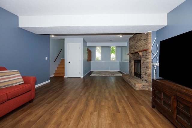107 Regal Dr, Normal, IL 61761 - unfurnished living room featuring stairs, dark wood-style floors, a brick fireplace, and beam ceiling