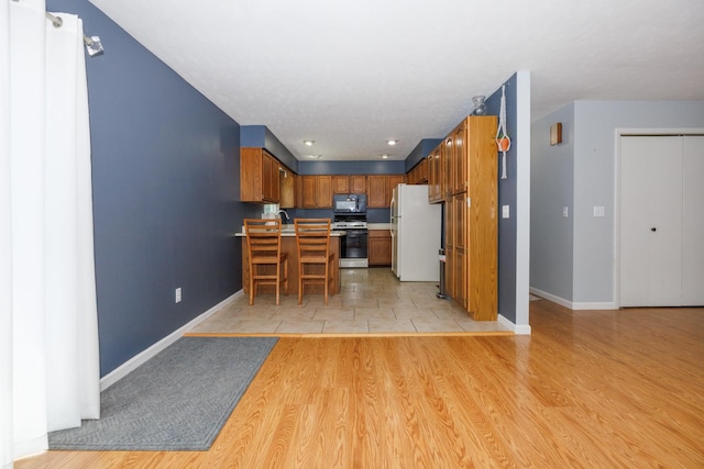 107 Regal Dr, Normal, IL 61761 - kitchen featuring white appliances, light countertops, brown cabinetry, a peninsula, and light wood-type flooring
