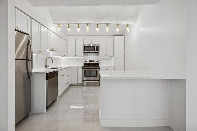 345 N Canal St Unit 1003, Chicago, IL 60606 - kitchen featuring appliances with stainless steel finishes, a sink, white cabinetry, a peninsula, and light stone countertops