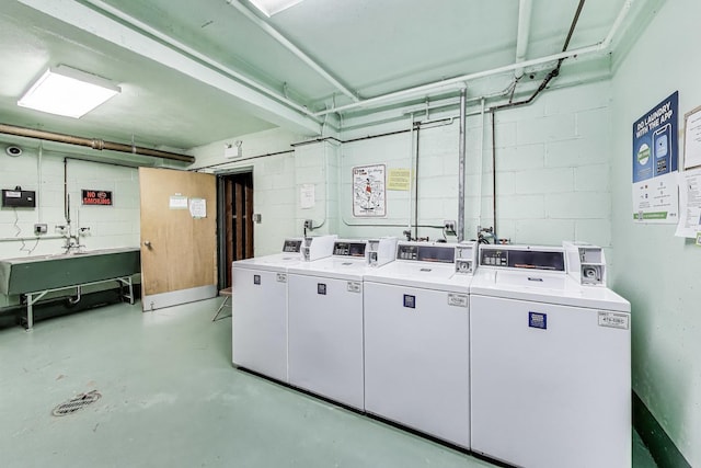 community laundry featuring washing machine and dryer and concrete block wall