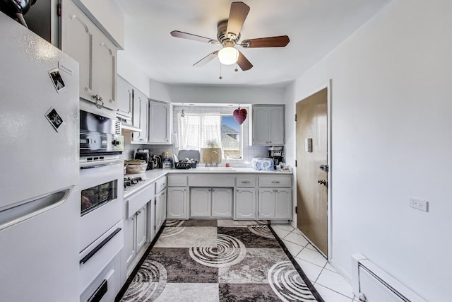 kitchen with freestanding refrigerator, backsplash, a ceiling fan, gray cabinets, and a baseboard heating unit