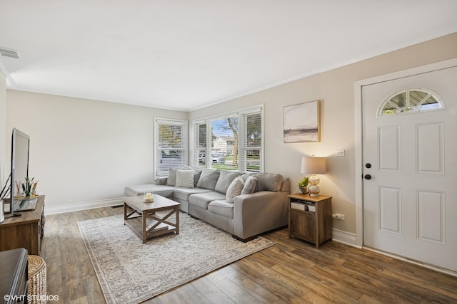 living area with dark wood finished floors, crown molding, and baseboards