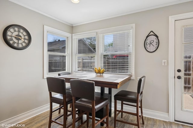 dining space with baseboards, ornamental molding, and wood finished floors