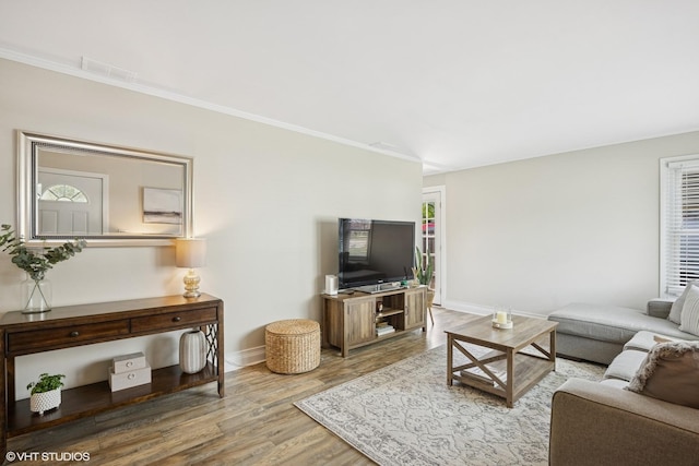 living room with wood finished floors, baseboards, and crown molding