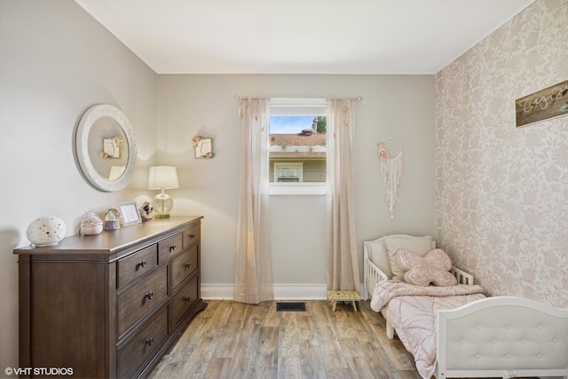 living area featuring wallpapered walls, light wood-style flooring, and baseboards