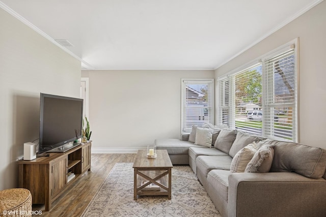living room featuring wood finished floors, baseboards, and crown molding