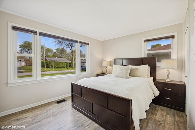bedroom with crown molding, wood finished floors, and baseboards