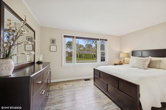 bedroom featuring light wood-style flooring, baseboards, and ornamental molding