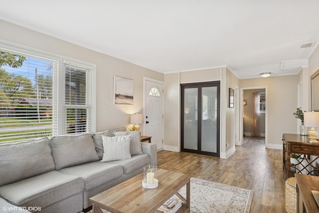 living area featuring wood finished floors, baseboards, and ornamental molding