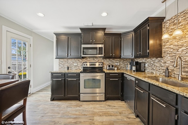 kitchen featuring stainless steel appliances, a sink, ornamental molding, light stone countertops, and backsplash