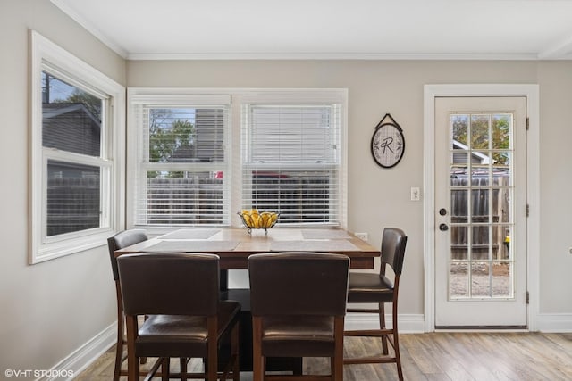 dining area featuring wood finished floors, baseboards, and ornamental molding