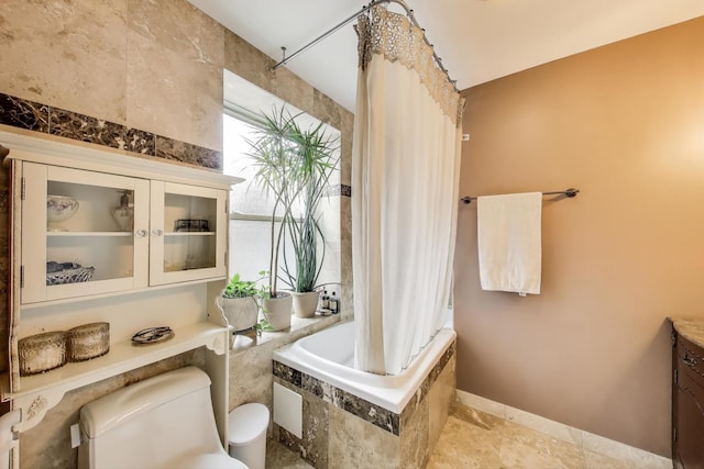 full bath with toilet, baseboards, tiled shower / bath, and vanity